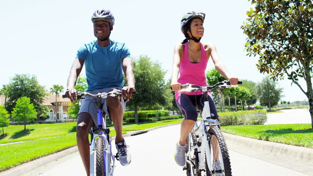 Young happy African American couple enjoying bike ride outdoors