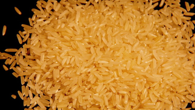 Looped: dry raw rice paddy cereal grains spinning slowly. Looped 4K UHD video footage.