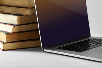 Stack of books with laptop on table close up