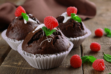 Delicious chocolate cupcakes with berries and fresh mint on wooden table close up