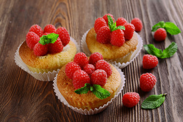 Delicious cupcakes with berries and fresh mint on wooden table close up