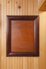 Classic wooden picture frame with blank canvas on wooden wall