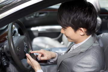 Businessman playing mobile phone inside car