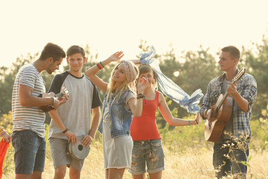 Joyful smiling friends dancing in the forest outdoors