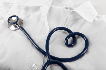 Heart shaped blue stethoscope, medical record and uniform, close up