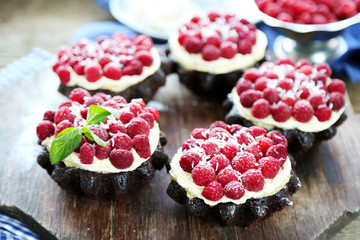 Sweet cakes with raspberries on wooden table background