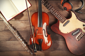 Electric guitar, violin, soprano saxophone, headphones and book on wooden background