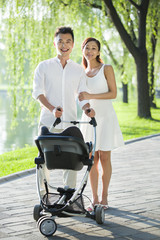 Fototapeta premium Young couple taking a walk with their baby in pram