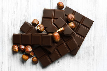 Chocolate pieces with nuts on color wooden background