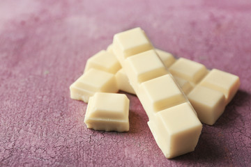 White chocolate pieces on color wooden background