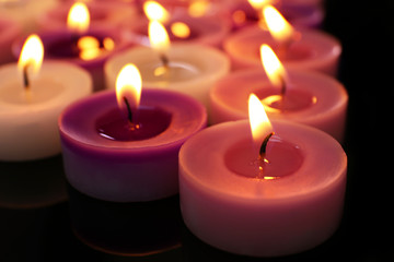 Fototapeta na wymiar Many burning small candles on dark background, close-up
