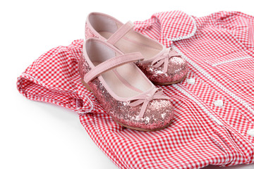 Shiny pink shoes and red plaid shirt on white background