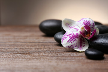Fototapeta na wymiar Black pebbles with orchid on wooden table