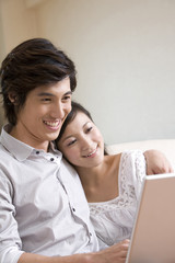 Fototapeta premium Asian couple cuddling on a sofa