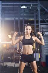 Young woman lifting weights at gym