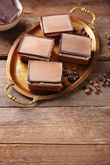Delicious chocolate brownies on tray, on wooden background