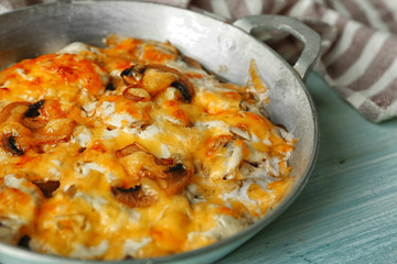 Roasted mushrooms, chicken and cheese gratin in pan, on wooden background
