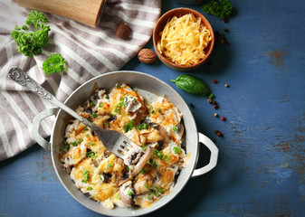 Roasted mushrooms, chicken and cheese gratin in pan, on color wooden background