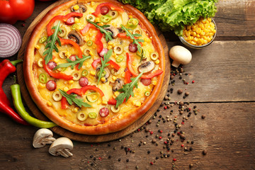 Delicious pizza with vegetables on wooden background