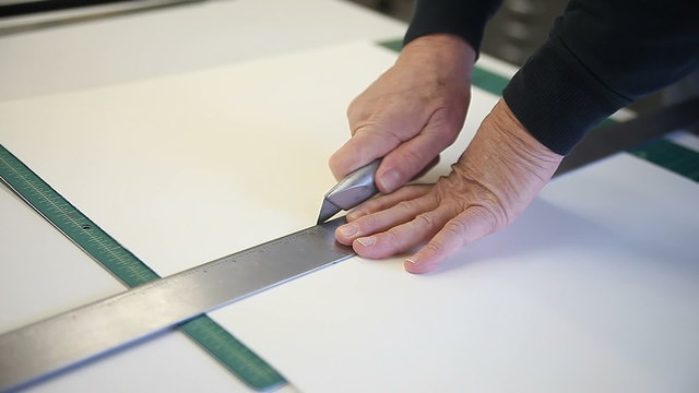 Man using box cutter to cut several sheets of paper at once