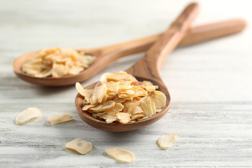 Two wooden spoons with almond flakes on the table, close-up