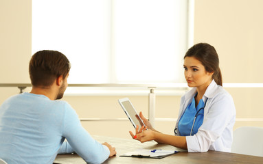 Obraz premium Doctor talking to male patient in room on light background