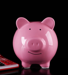 Piggy bank with calculator on dark background