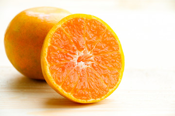Fototapeta na wymiar Organic orange fruit. Slices on soft wooden background