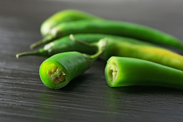 Green chili peppers on dark wooden background