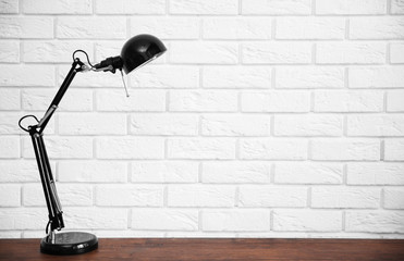 Modern lamp on table on brick wall background