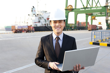 businessman using a laptop at a shipping port