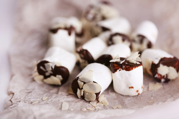 Tasty marshmallows with chocolate on paper, close up
