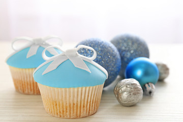 Tasty cupcakes with bow and Christmas toys on color wooden background