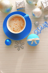 Tasty cupcake with bow, coffee cup and Christmas toys on color wooden background