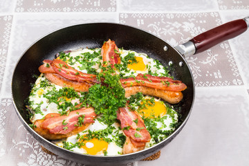 Delicious bacon strips, sausages and fried eggs breakfast in pan