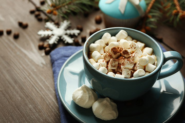 Mug of hot chocolate with marshmallows, fir tree branch on wooden background