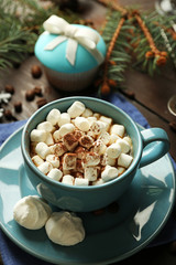 Mug of hot chocolate with marshmallows, fir tree branch on wooden background