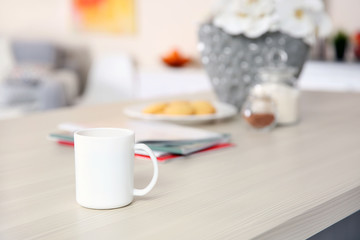 Cup of coffee on wooden table in the kitchen, close up