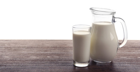 Milk in glass and in jar on table isolated on white background