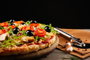 Delicious tasty pizza with cutter on black background
