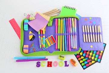 Pencil case with various stationery on wooden table