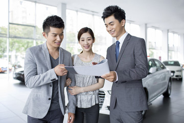 Young couple choosing car in showroom