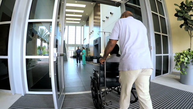 Asian American doctor welcome senior disabled couple in hospital atrium