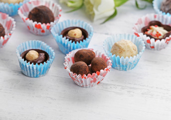 Set of chocolate candies with flowers on a light wooden background