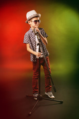 Little boy singing with microphone on a bright background