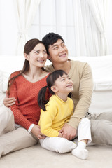 Fototapeta premium Happy young family sitting on carpet