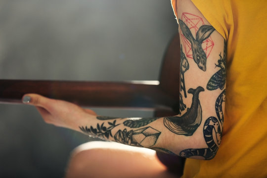 Woman's hand with tattoo playing guitar