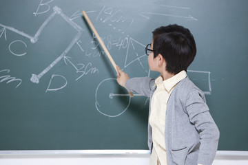 Active little boy playing teacher in classroom