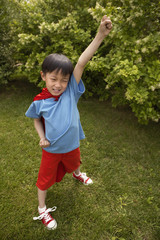 Obraz premium Boy In Red Cape Playing In Garden