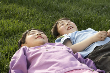 Young Boy And Girl Laying In The Park Looking At The Sky